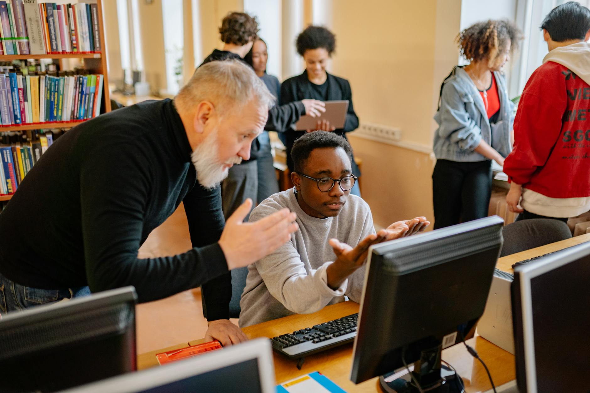 a teacher and a boy in front of a computer